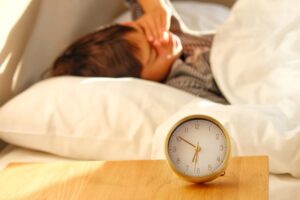 夜勤明けに頭痛で頭を押さえる女性