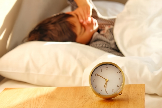 夜勤明けに頭痛で頭を押さえる女性