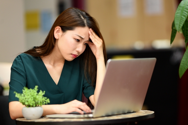 額に手を当て、眉間にしわを寄せて考えこむ女性