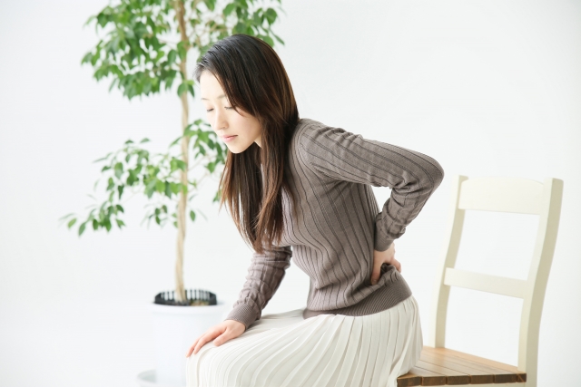 白い椅子に浅く腰かけている女性