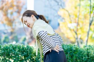 背中の後ろに手を回す女性