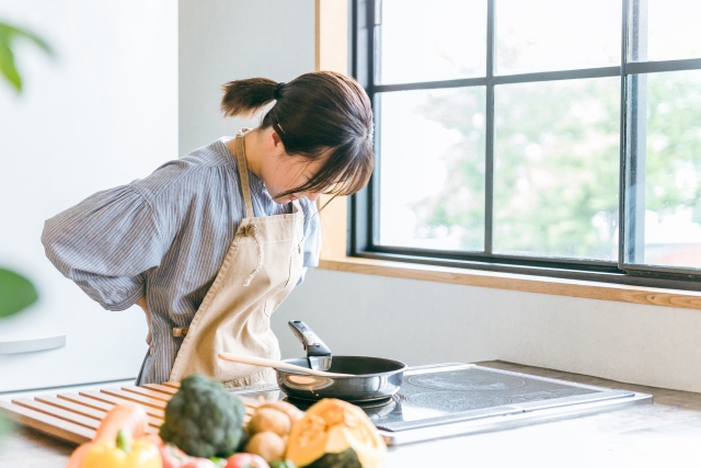 キッチンで調理中に腰に手を当てる女性
